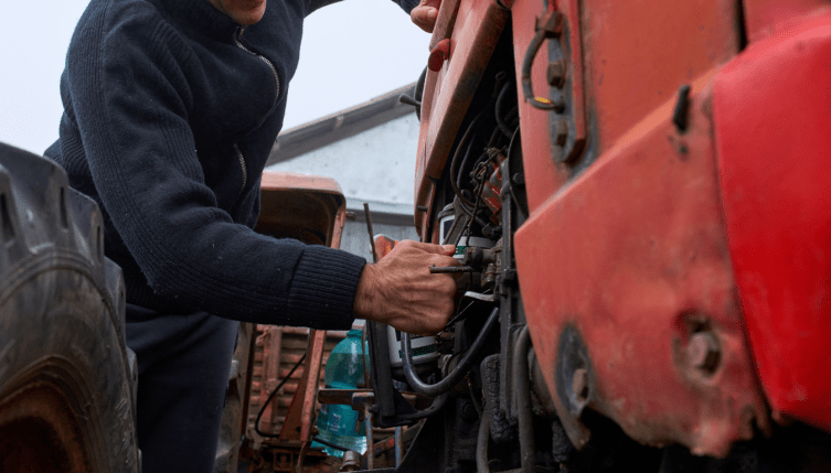 Operario revisando un tractor para realizar mantenimiento correctivo vs preventivo